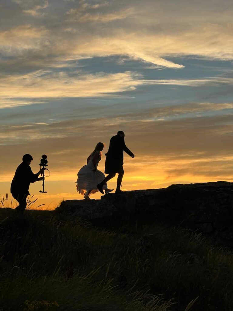 second shooter filming couple with stunning sunset backdrop