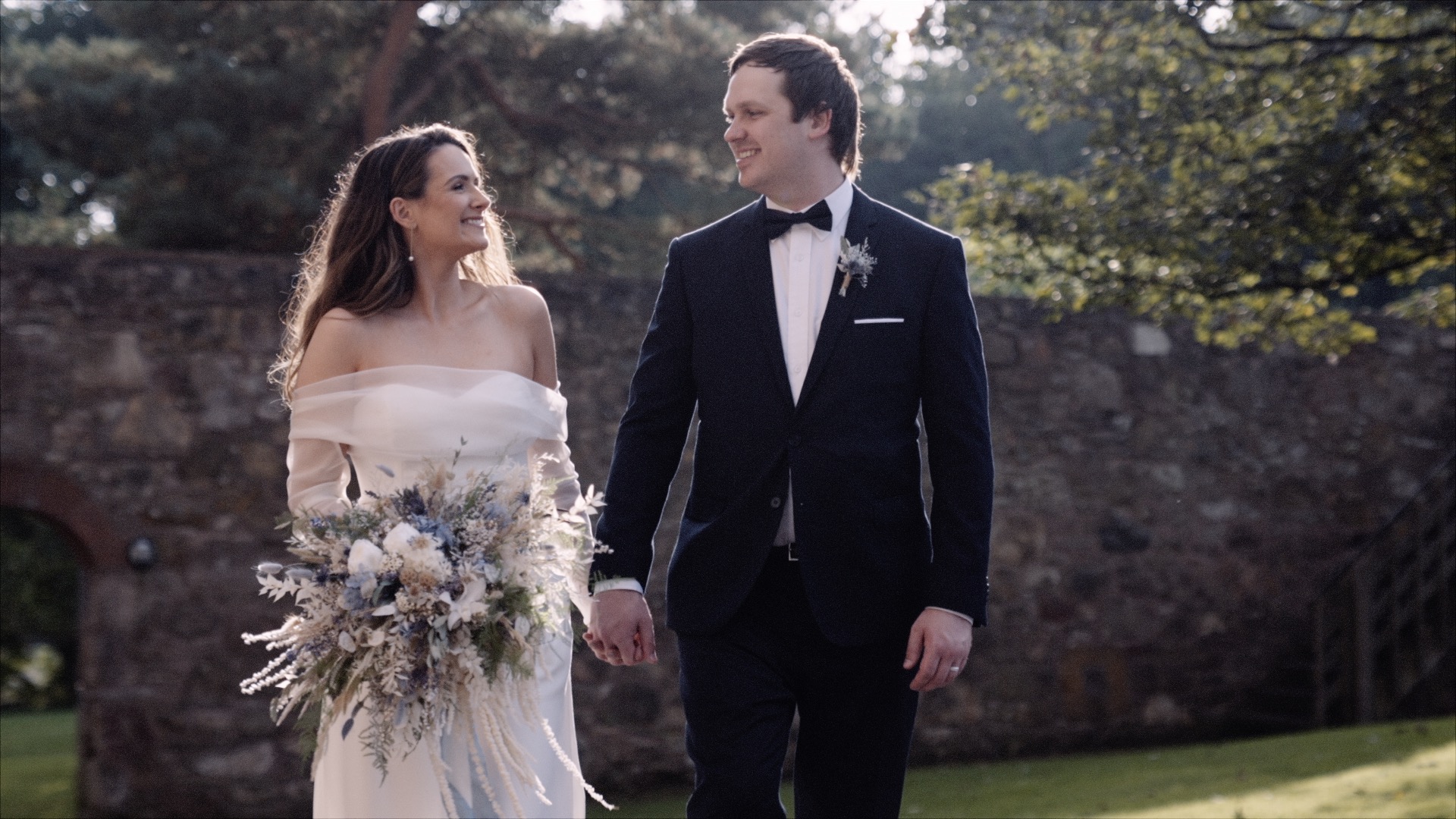 ro and andy walking together as bride and groom in a walled garden