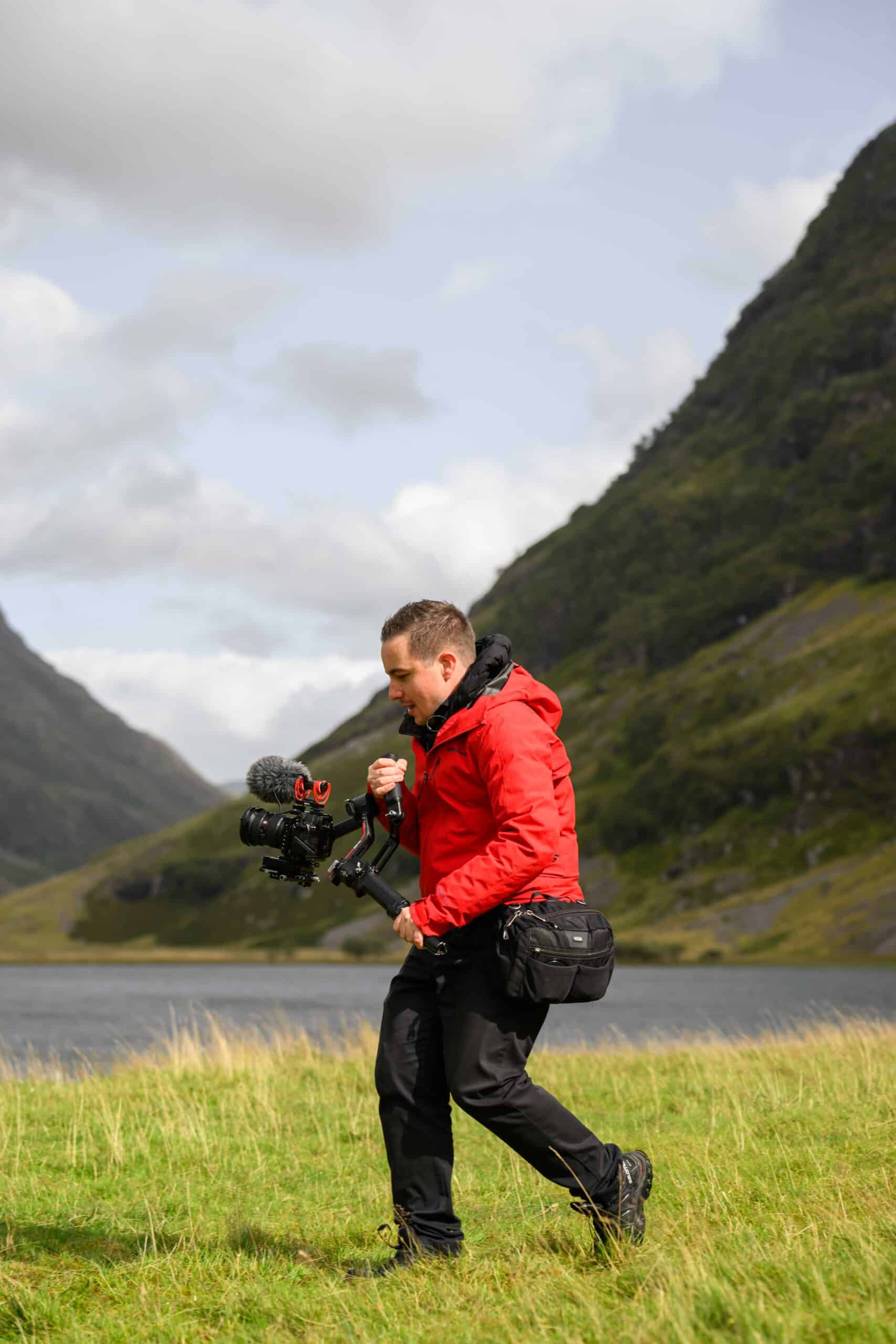 Michael Westcott Films using a gimbal in glencoe wearing a red jacket