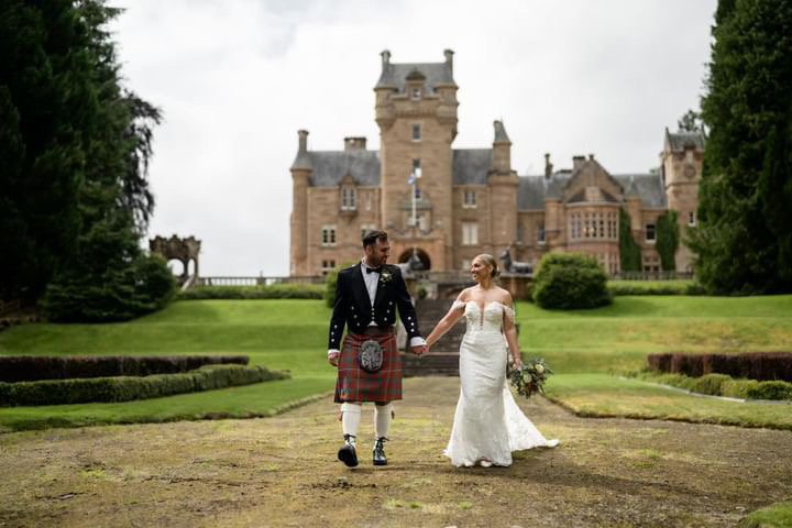 wedding couple holding hands with ardross castle in background