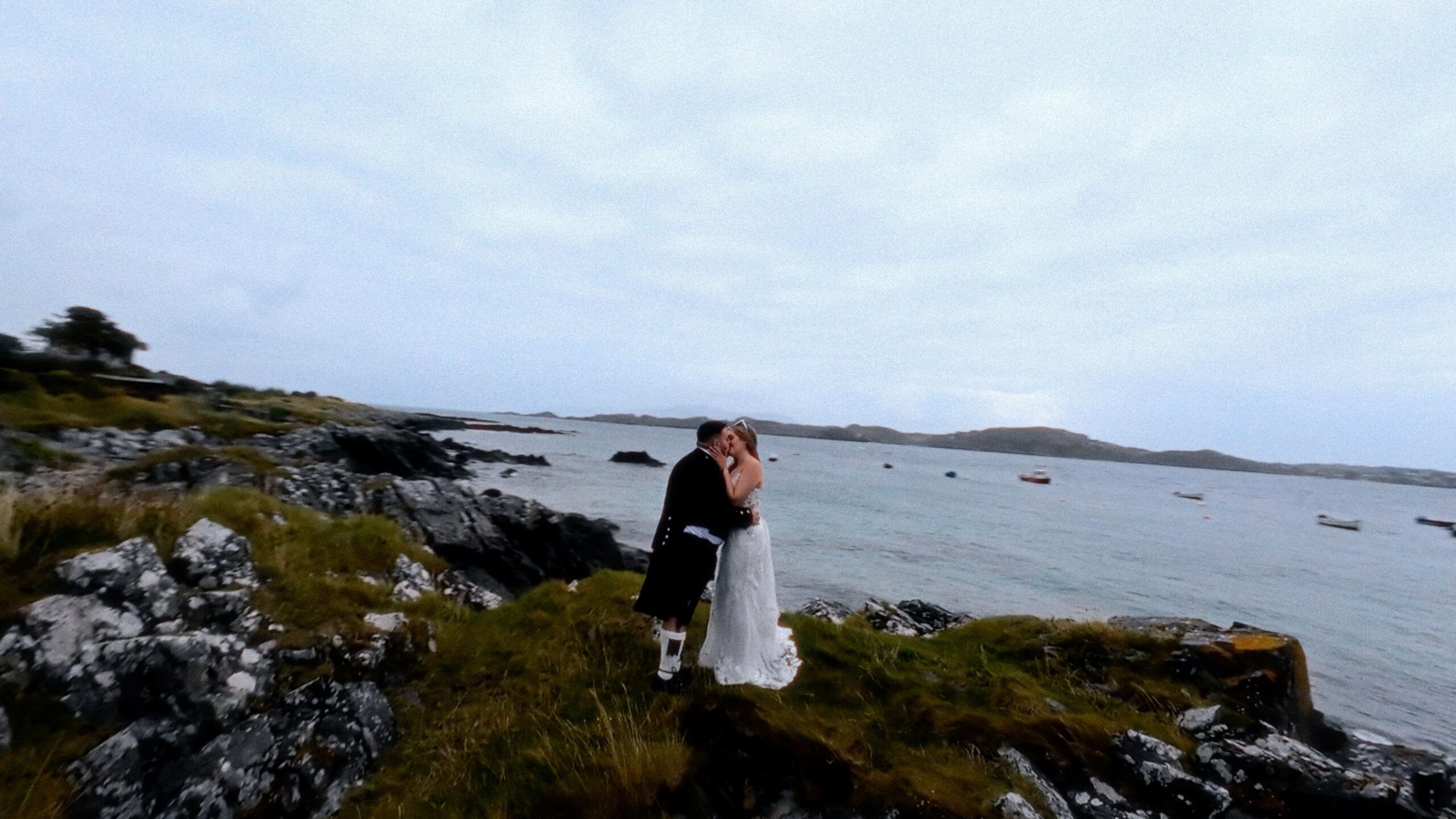 bride and groom kissing on the coast of Iona in Scotland. picture taken from a drone